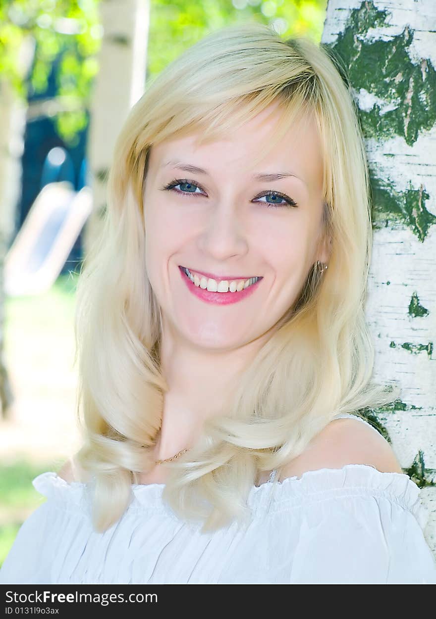 Portrait of pretty blonde girl near of birch stem