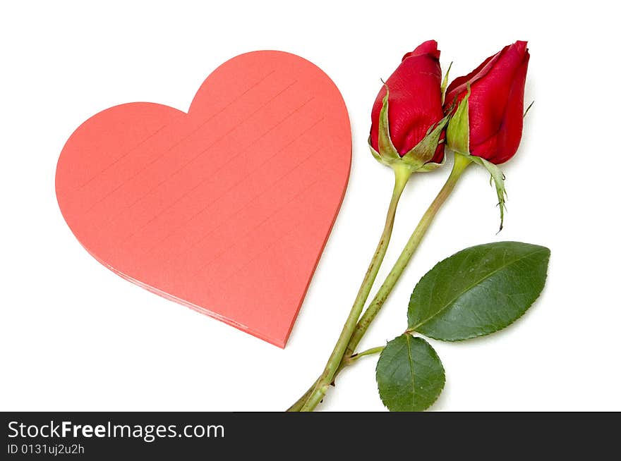 Love note in heart shaped pad next to a couple of red roses. Love note in heart shaped pad next to a couple of red roses