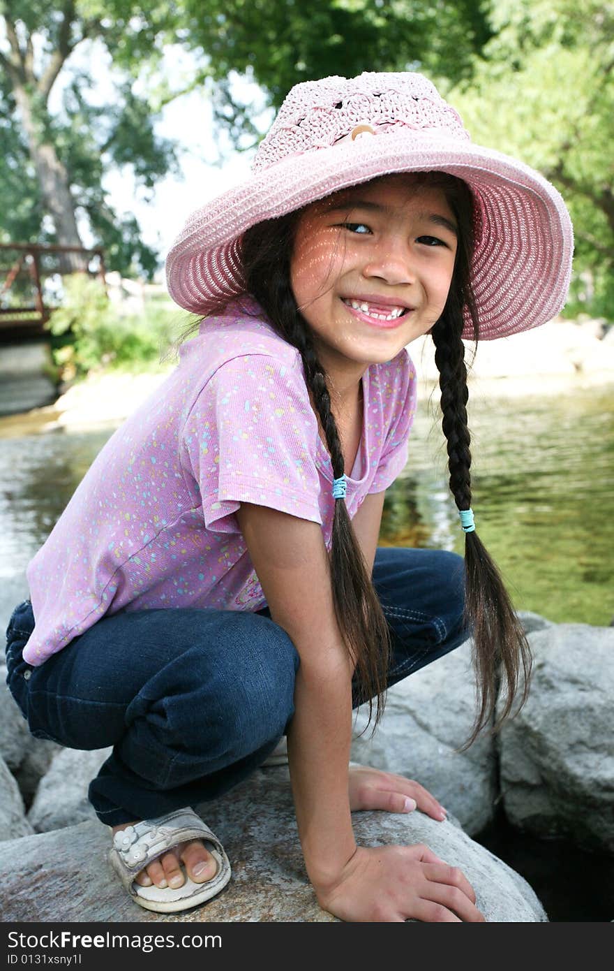 Little girl playing on rocks by river