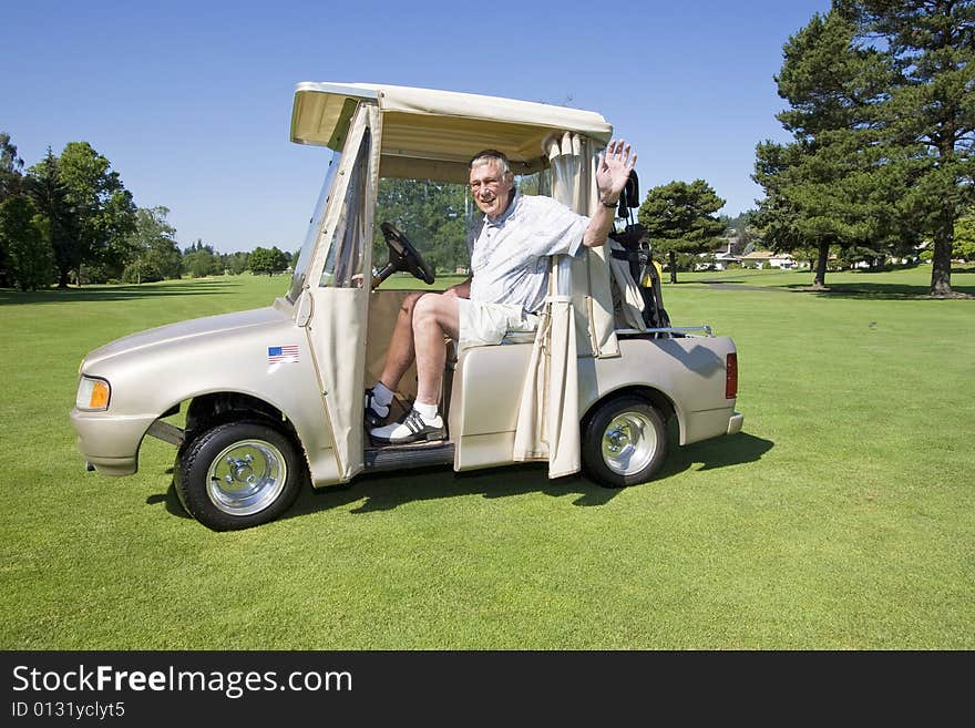 Elderly man smiling and waving while riding in a golf cart. Horizontally framed photo. Elderly man smiling and waving while riding in a golf cart. Horizontally framed photo.