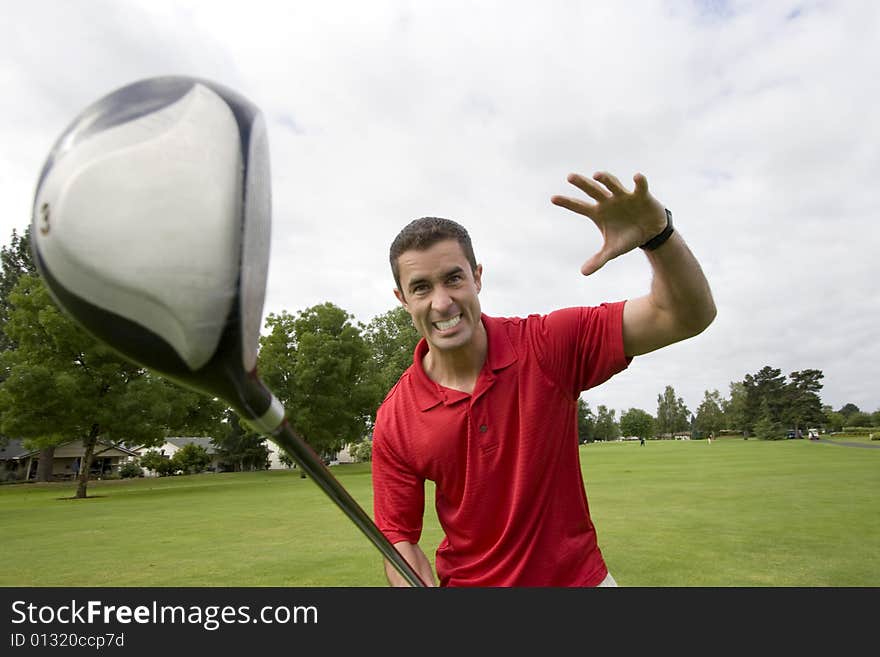 Man holding golf club away from him while he pretends to attack it. Horizontally framed photo. Man holding golf club away from him while he pretends to attack it. Horizontally framed photo.