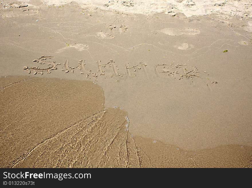 The word summer written in the sand with an approching wave. The word summer written in the sand with an approching wave