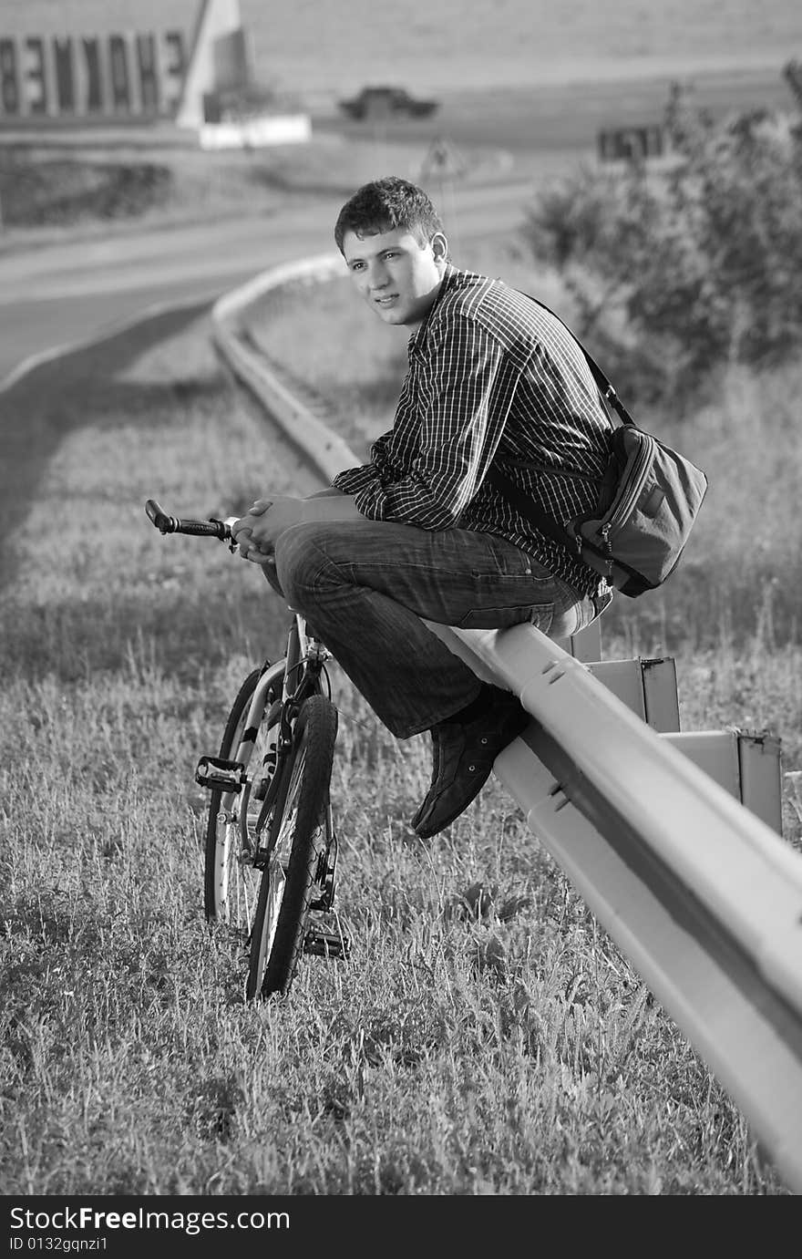 A young man with a bicycle on the highway. A young man with a bicycle on the highway