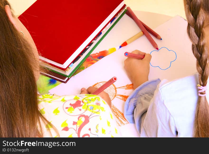 Two girls are drawing by color pencils