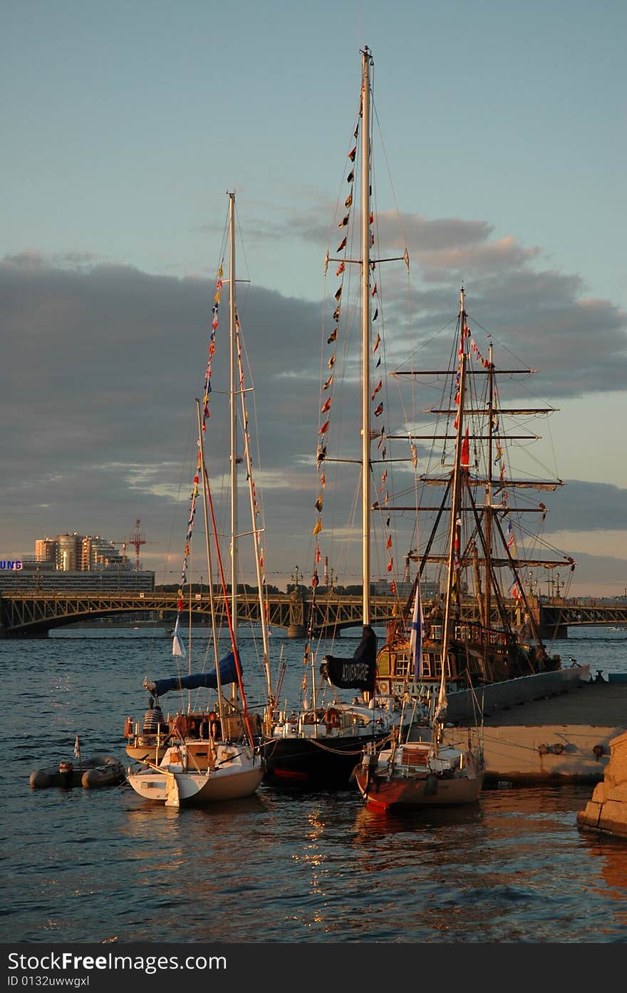 Boats and sailing-vessel on the river by a summer warm, sun evening