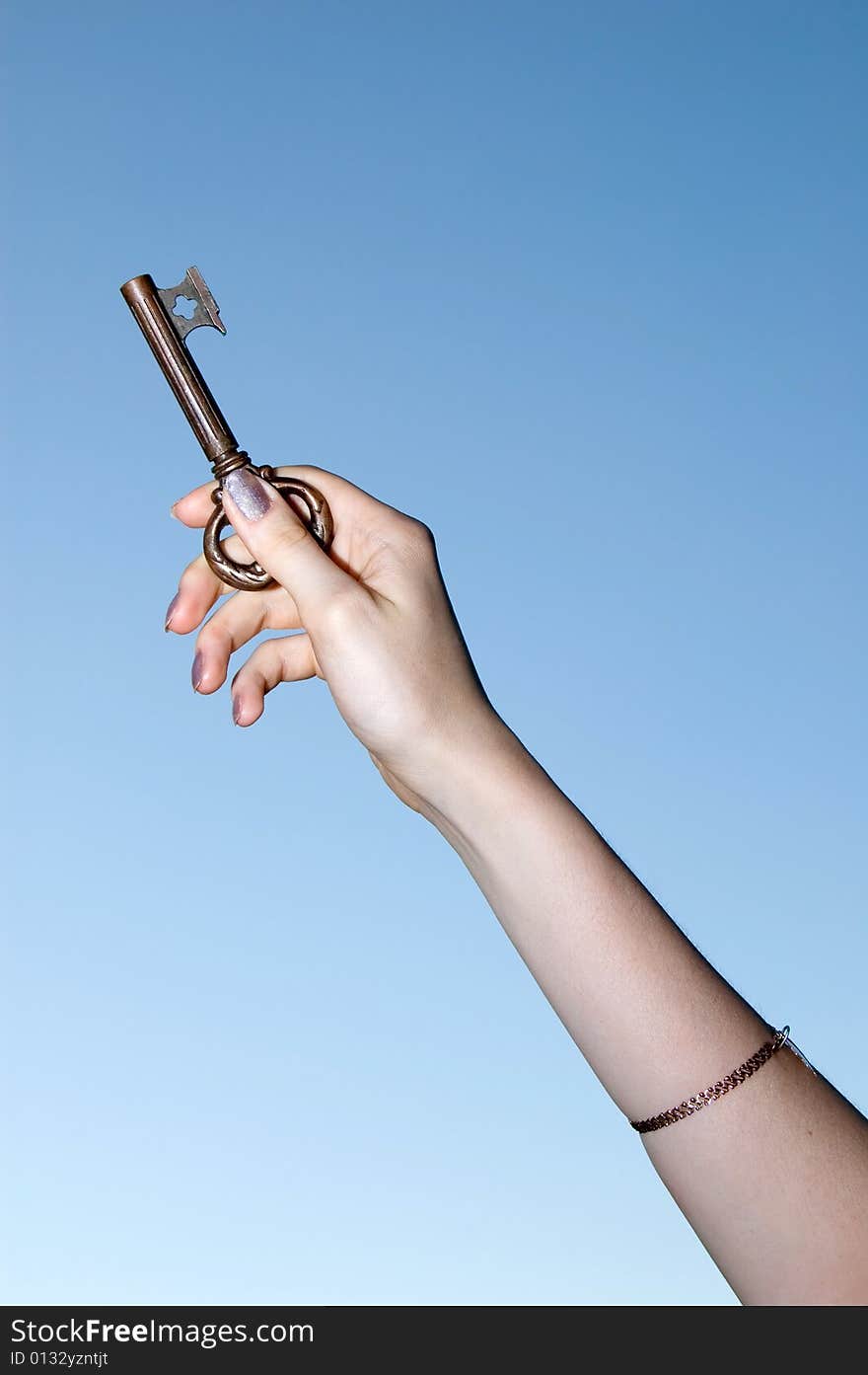 Gold key in a hand against the sky