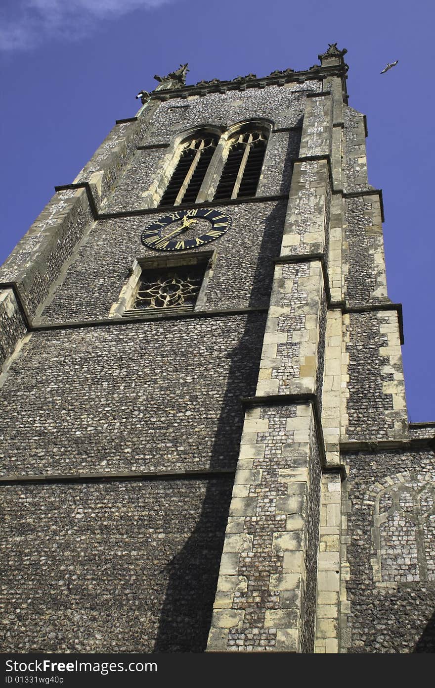 Old church tower taken from directly below with the blue sky above