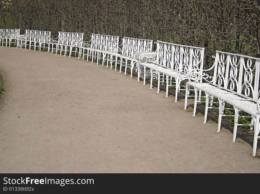 Seven white benches in park