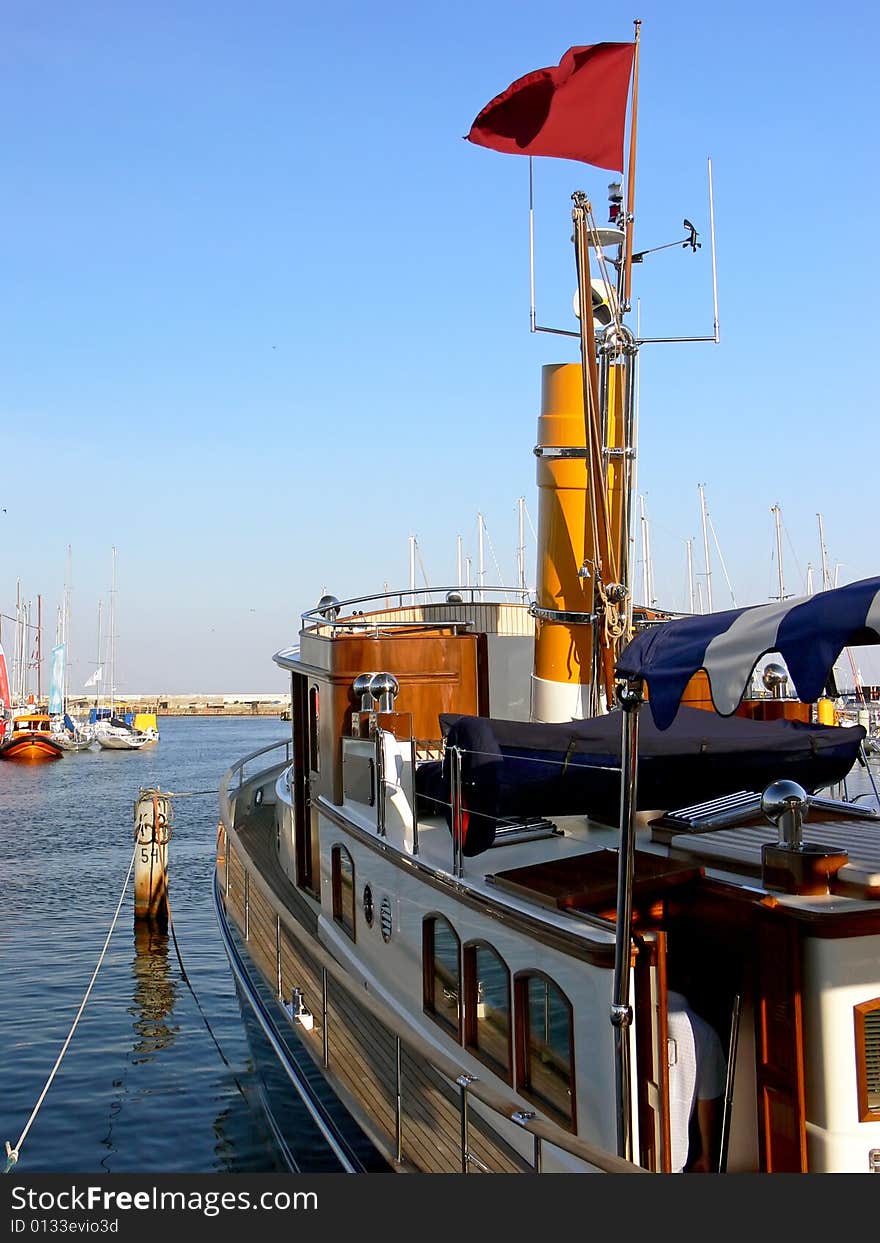 Luxury steam ship with yellow chimney moored in harbour.