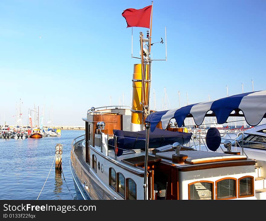 Luxury steam ship with yellow chimney moored in harbour.