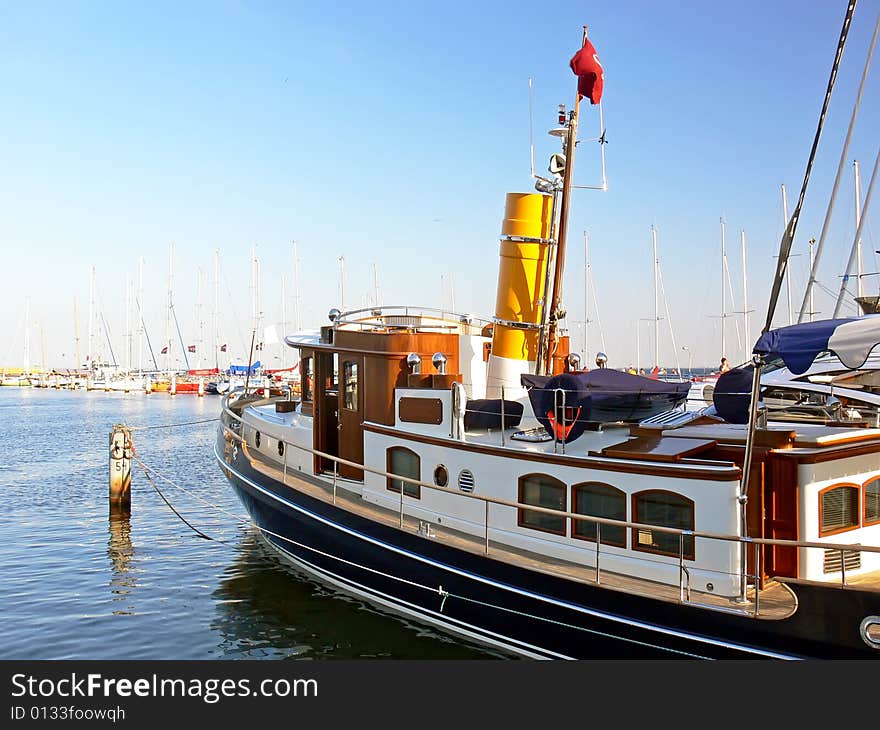 New steam ship with yellow chimney moored in harbour.