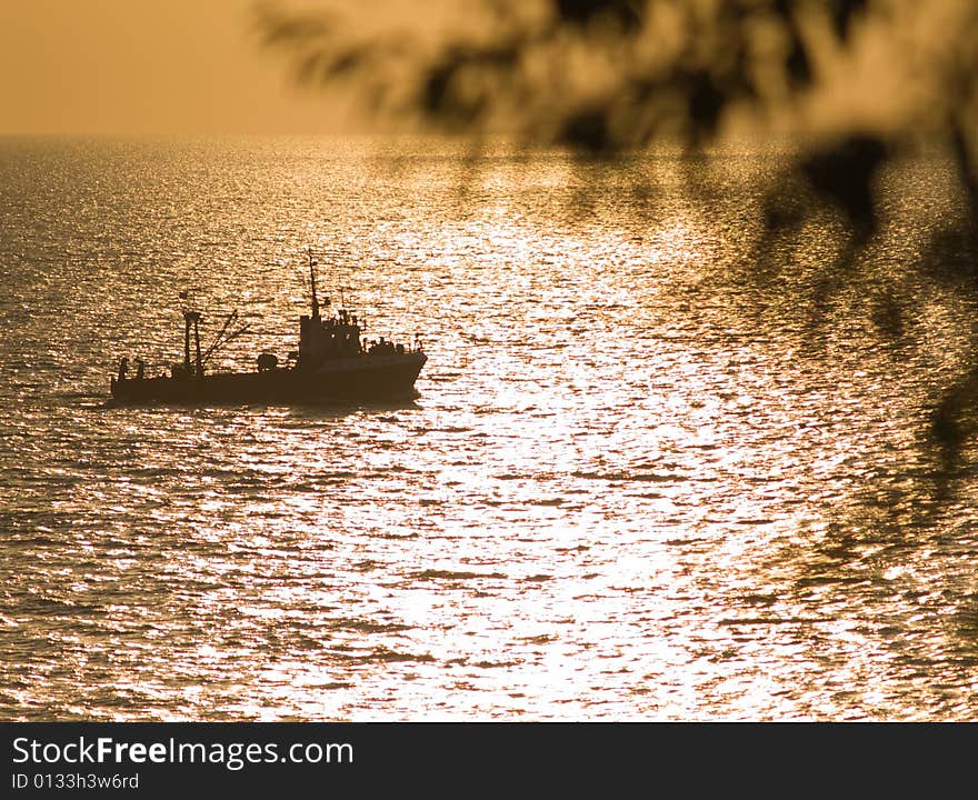 Small fishing ship floating on sunset