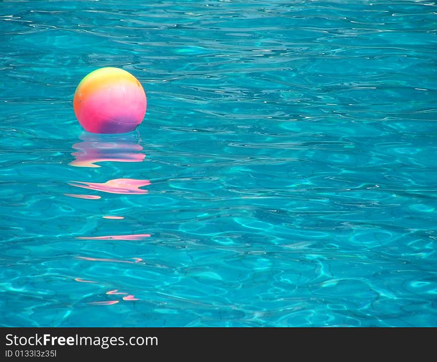 Rainbow-colored ball in swimming pool. Rainbow-colored ball in swimming pool