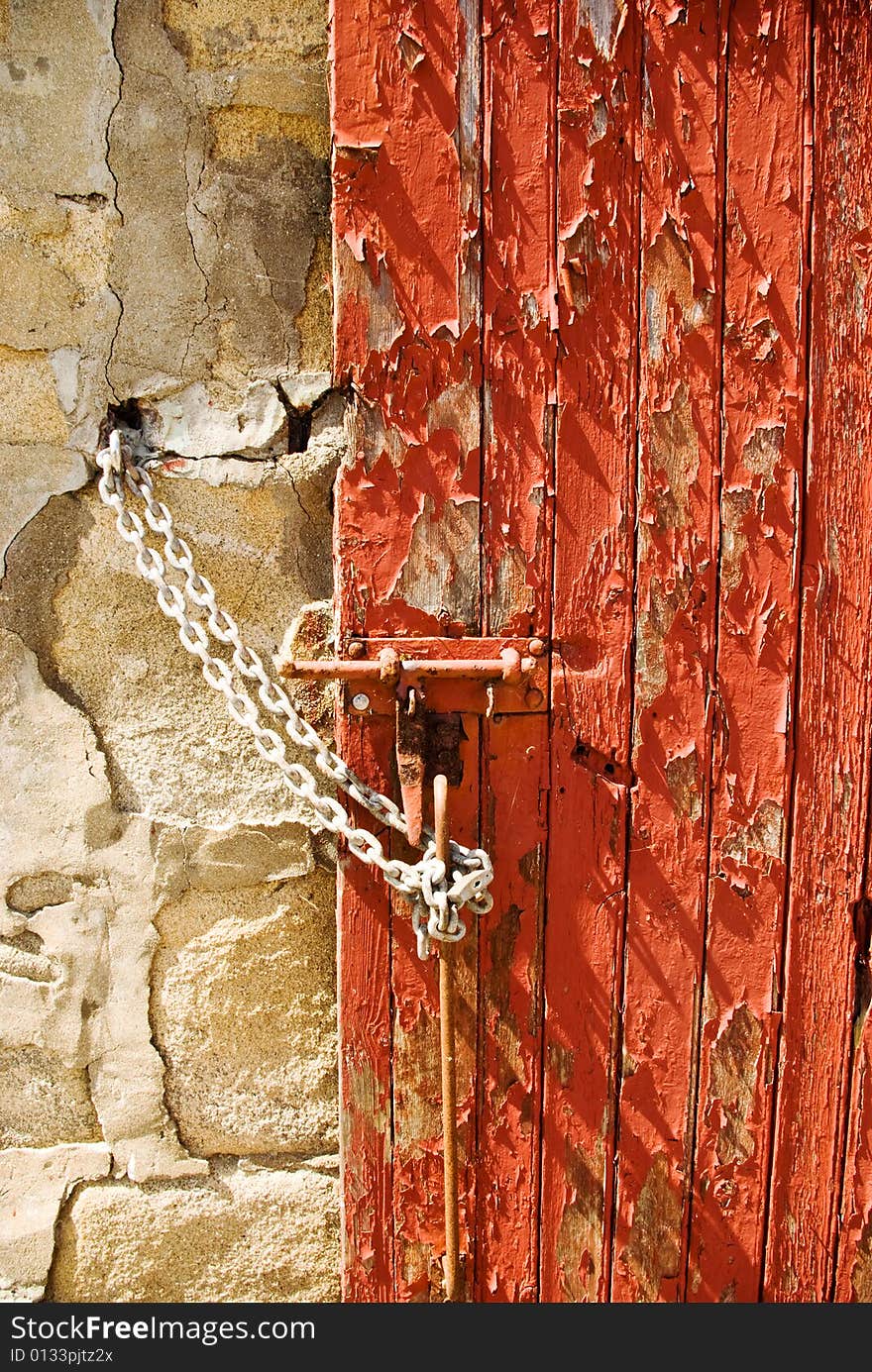 The texture and pattern of peeling red paint on a door. The texture and pattern of peeling red paint on a door