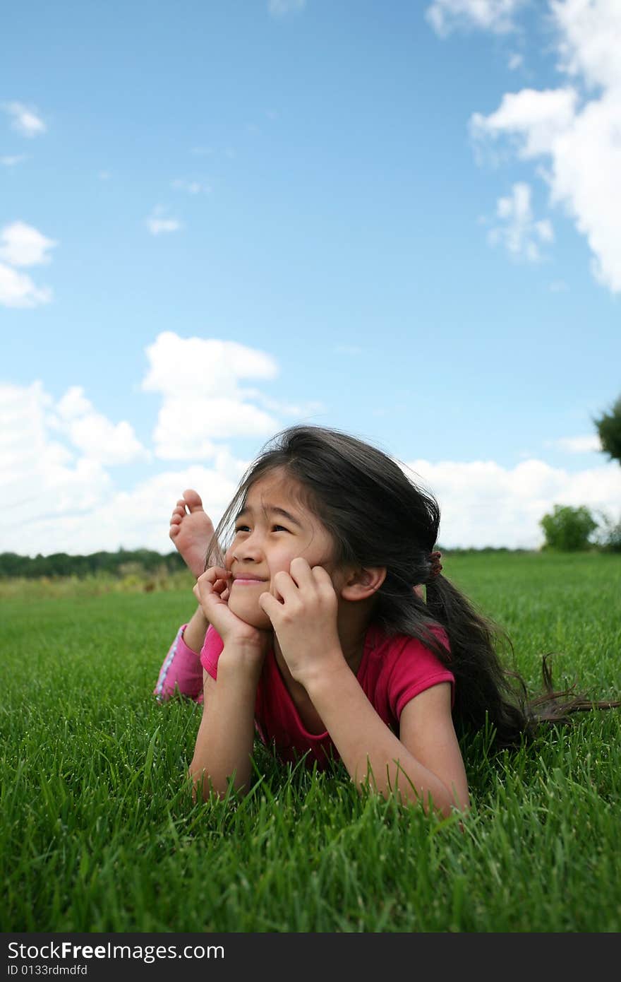 Little girl lying on grass in summer