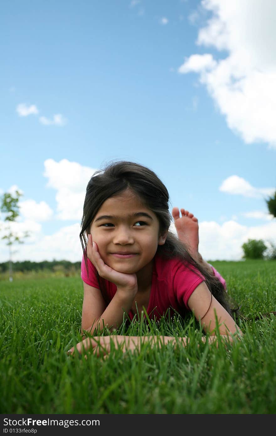 Little girl lying on grass in summer