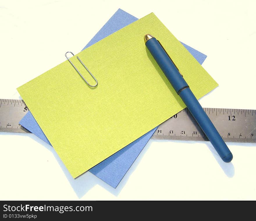 Pen, colored papers, and ruler against white background. Pen, colored papers, and ruler against white background