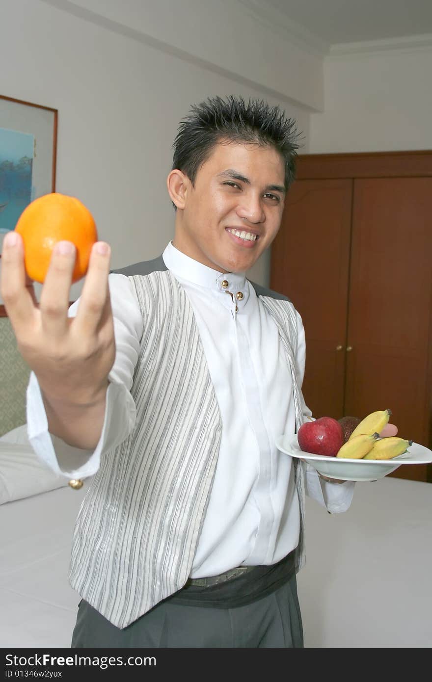 Room service waiter deliver fruit in hotel room smiling