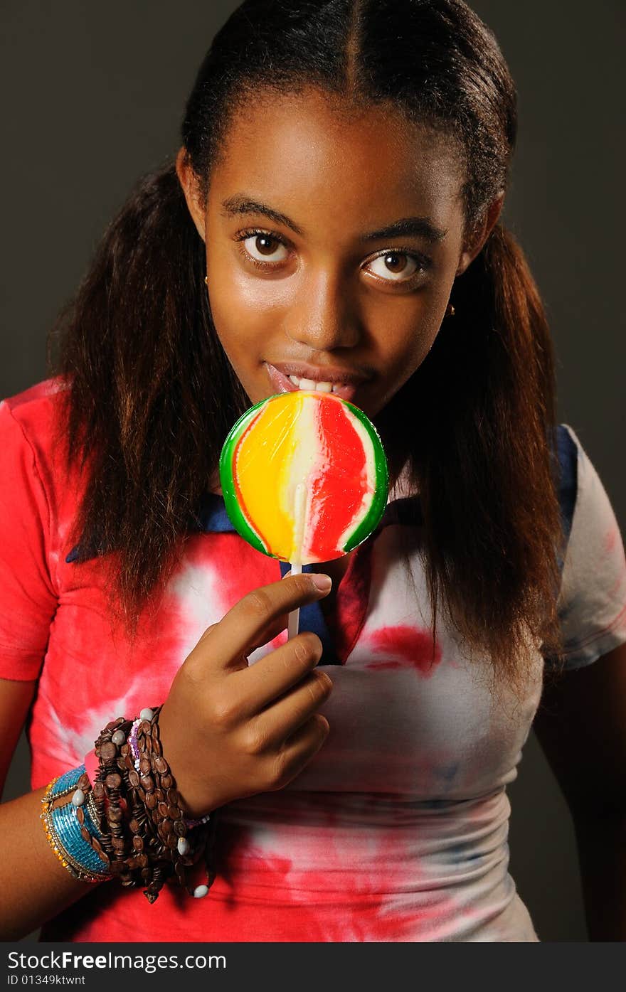 Portrait of young african girl eating a lollipop with happy expression. Portrait of young african girl eating a lollipop with happy expression