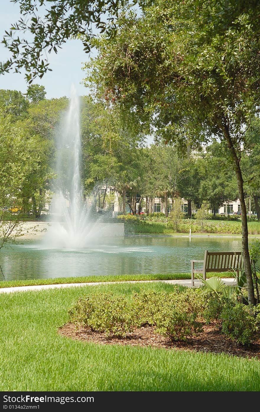 Parkbench and fountain at park.