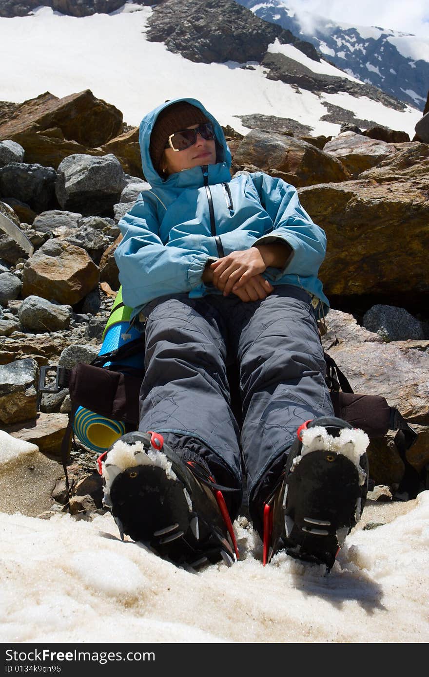 Girl in crampon relaxing on snow in mountains