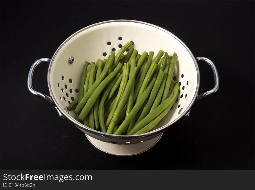 Kitchen colander filled with green beans brightly lit on isolated white background. Kitchen colander filled with green beans brightly lit on isolated white background