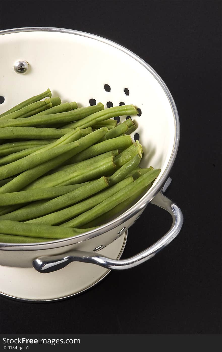 Kitchen colander filled with green beans brightly lit on isolated white background. Kitchen colander filled with green beans brightly lit on isolated white background