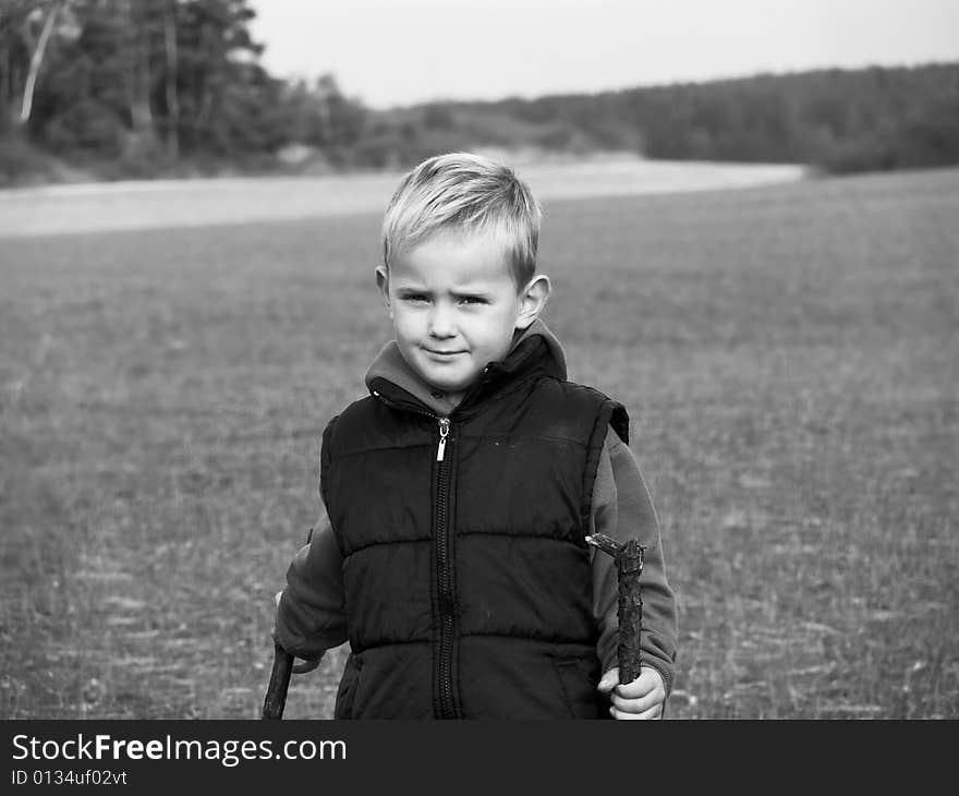 The small boy is playing in the meadow - the photo is in black and white. The small boy is playing in the meadow - the photo is in black and white