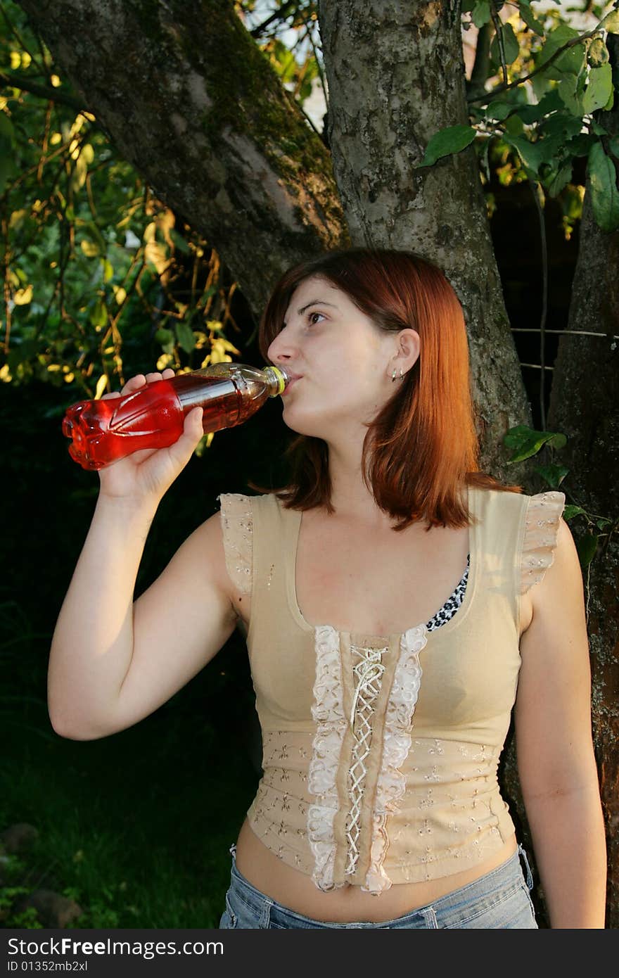 The girl drinks a water from a plastic bottle. The girl drinks a water from a plastic bottle