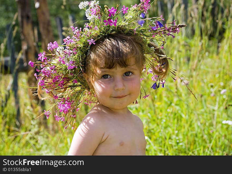 The little girl in wildflower diadem modestly smiles. The little girl in wildflower diadem modestly smiles