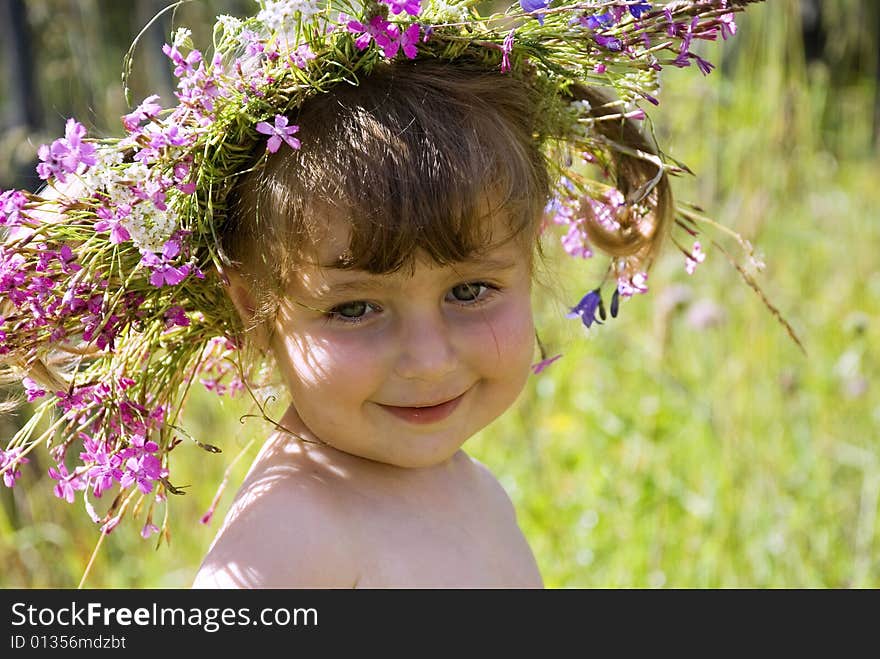 The little girl in wildflower diadem modestly smiles. The little girl in wildflower diadem modestly smiles