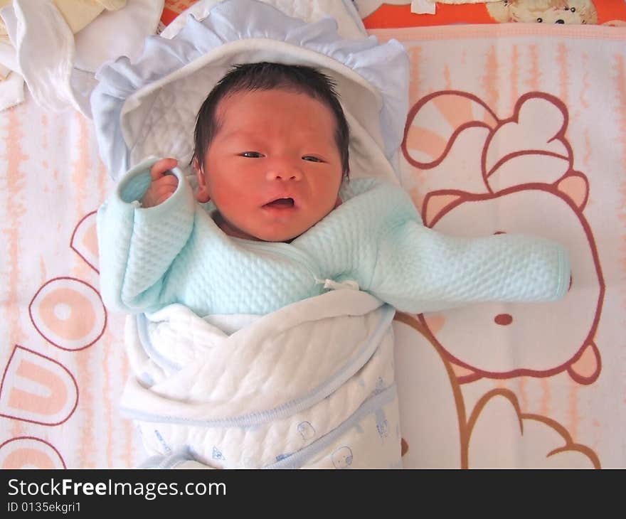 A Chinese baby on a bed with her mouth opening. A Chinese baby on a bed with her mouth opening