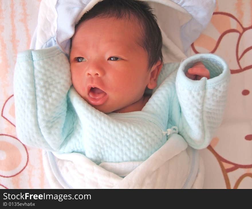 A Chinese baby on a bed, opening her mouth. A Chinese baby on a bed, opening her mouth