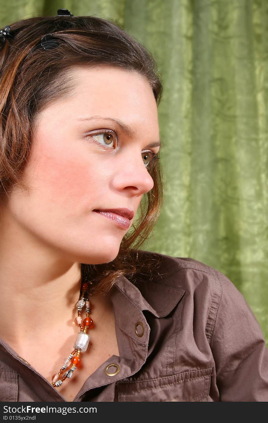 Beautiful brunette female wearing a brown shirt against a green background. Beautiful brunette female wearing a brown shirt against a green background