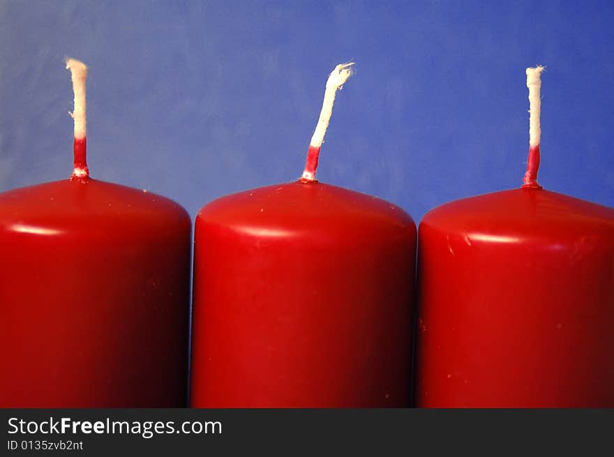 Set of three red candles over teh blue background. Set of three red candles over teh blue background