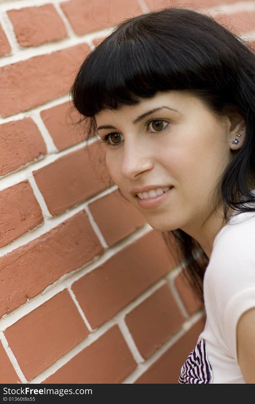 Closeup portrait of young pretty brunet girl against brick wall