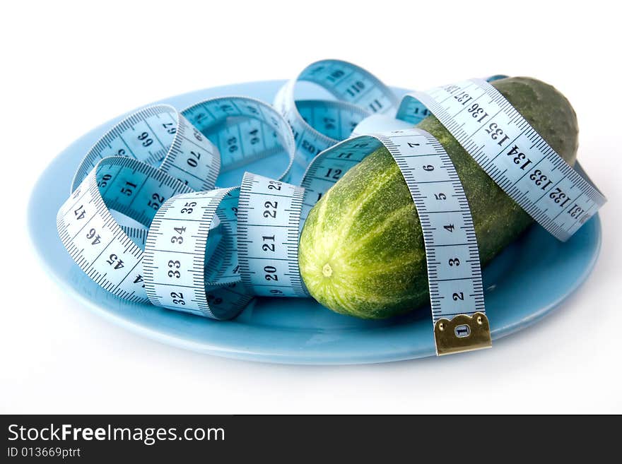 Green fresh cucumber bound with tape measure on a blue plate. Green fresh cucumber bound with tape measure on a blue plate