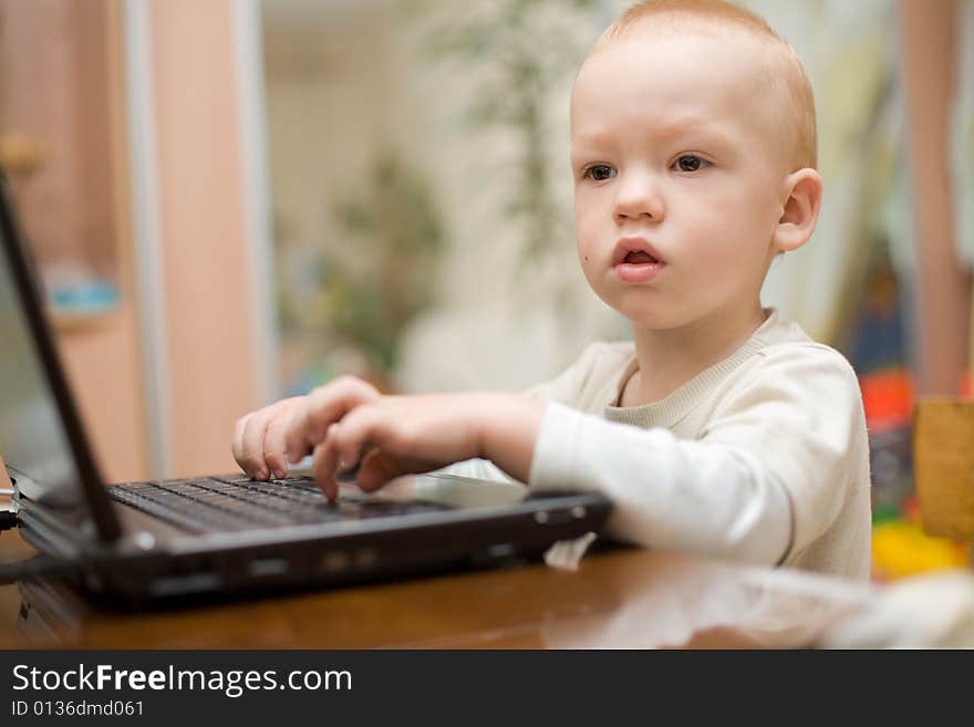 Little boy typing text on laptop at home