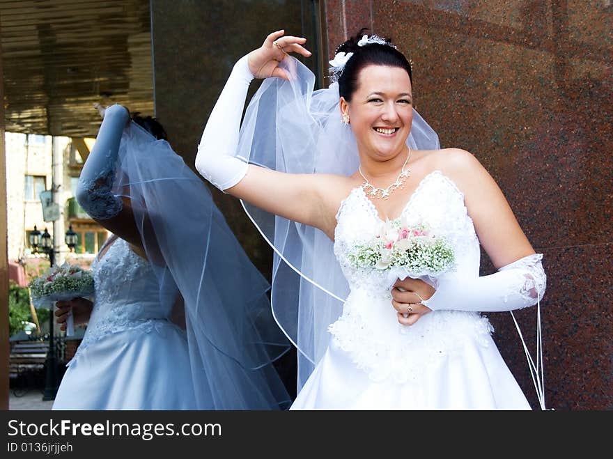 Cheerful bride holding her veil outdoor