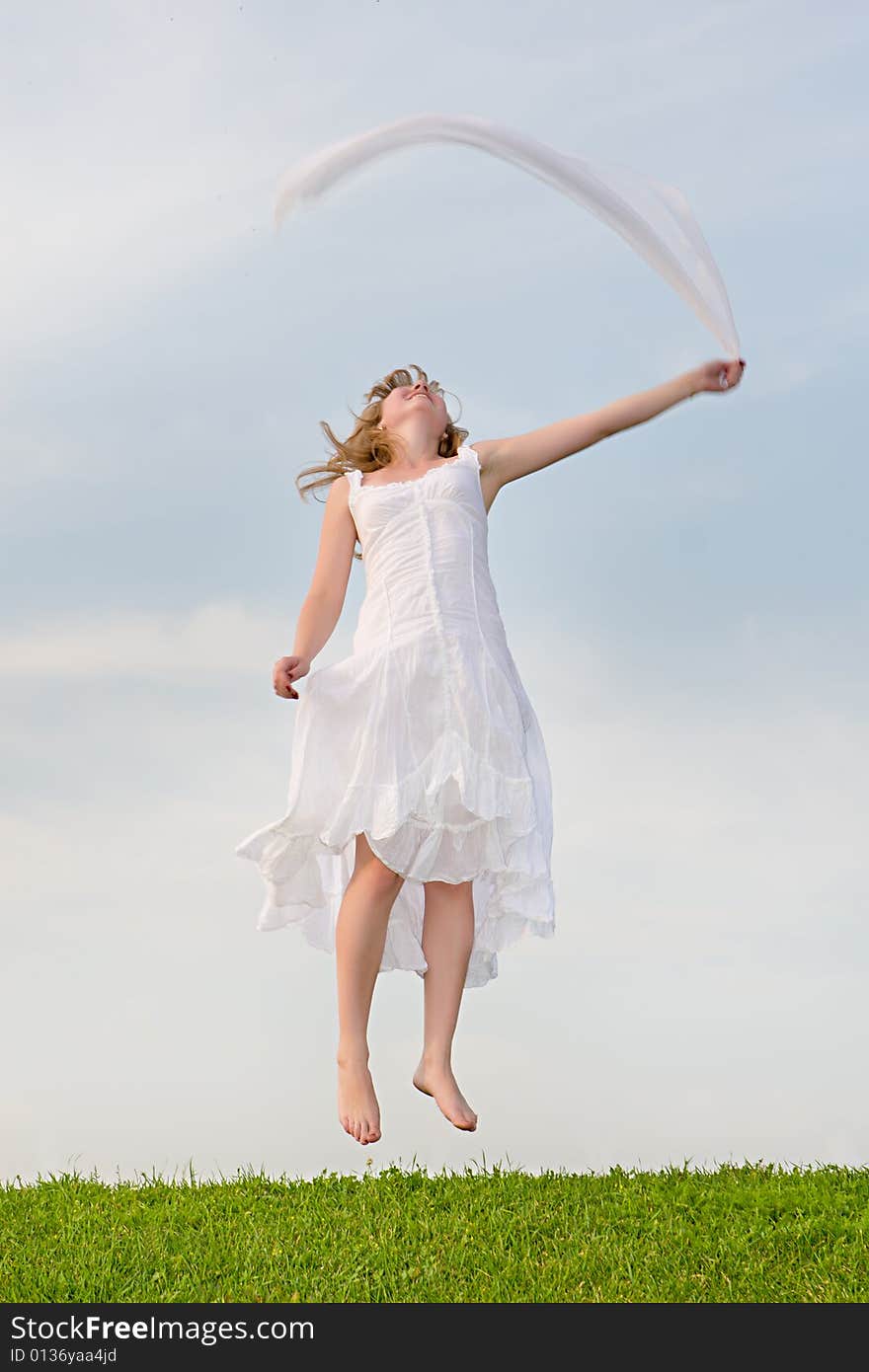 Girl jumps on a green grass on a background of the blue sky. Girl jumps on a green grass on a background of the blue sky