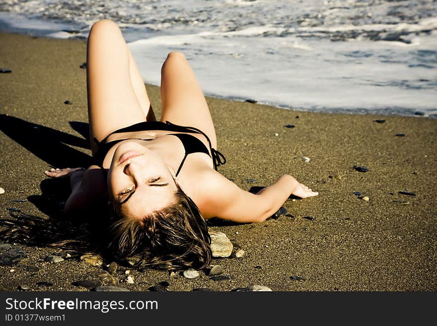 Laying green eyed beauty wearing black small bikini.