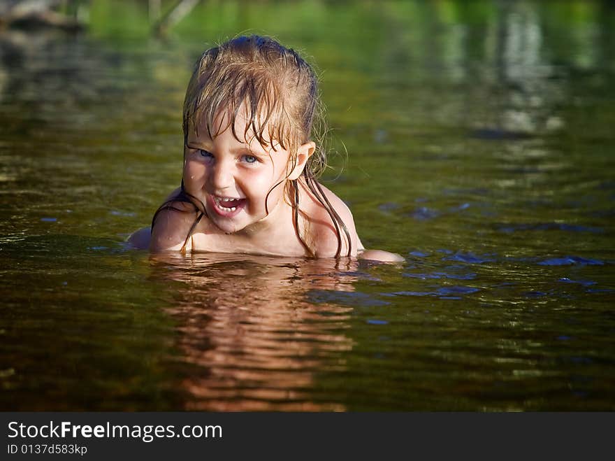 Charmed little girl sits waters of the lake and laughs. Sunshine, 
summer. Charmed little girl sits waters of the lake and laughs. Sunshine, 
summer