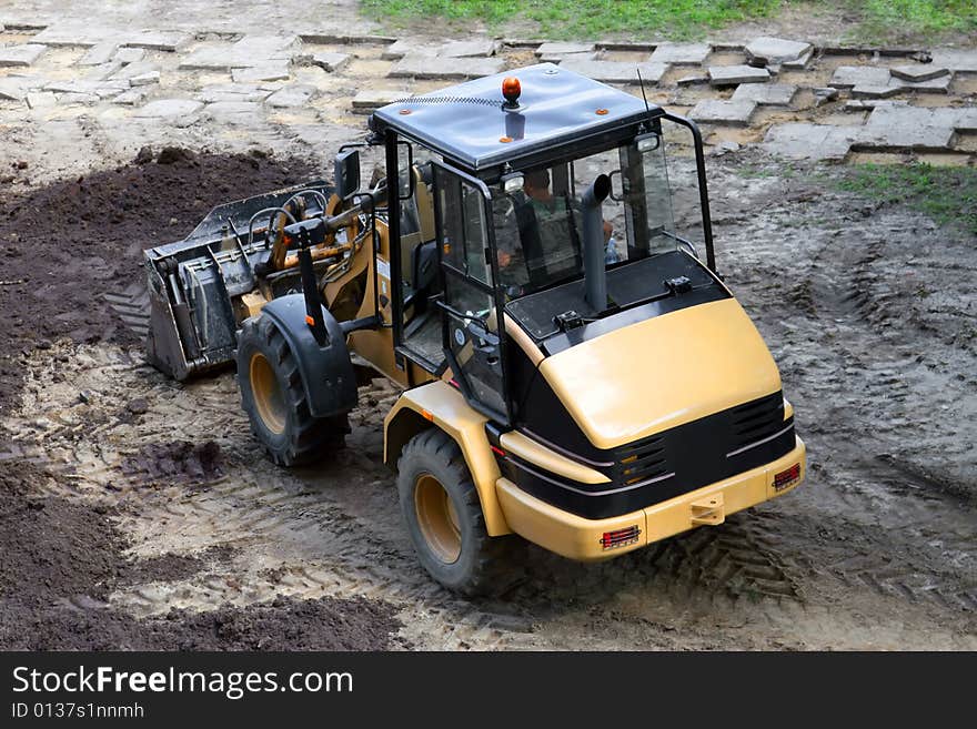 Construction Vehicle.  Sidewalk and black earth in the background. Construction Vehicle.  Sidewalk and black earth in the background