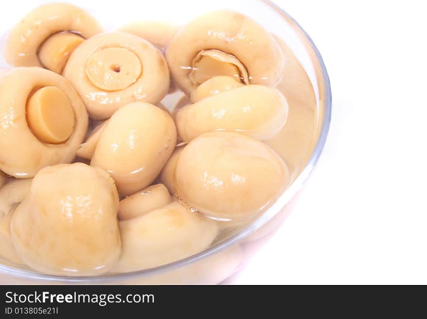 Conserved mushrooms in the glass on the white background. Conserved mushrooms in the glass on the white background