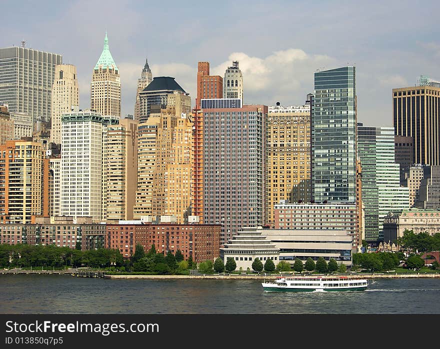 The view of Manhattan filled with sunset light and a ferry sailing around (New York City). The view of Manhattan filled with sunset light and a ferry sailing around (New York City).