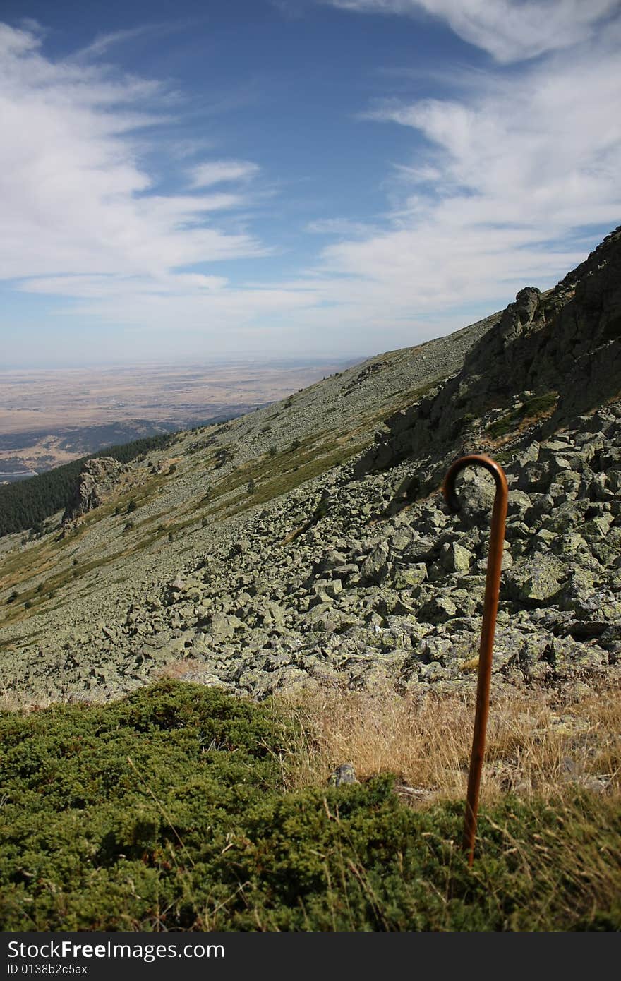 A cane is planted in the ground, beyond it can be seen a high mountain panorama. A cane is planted in the ground, beyond it can be seen a high mountain panorama