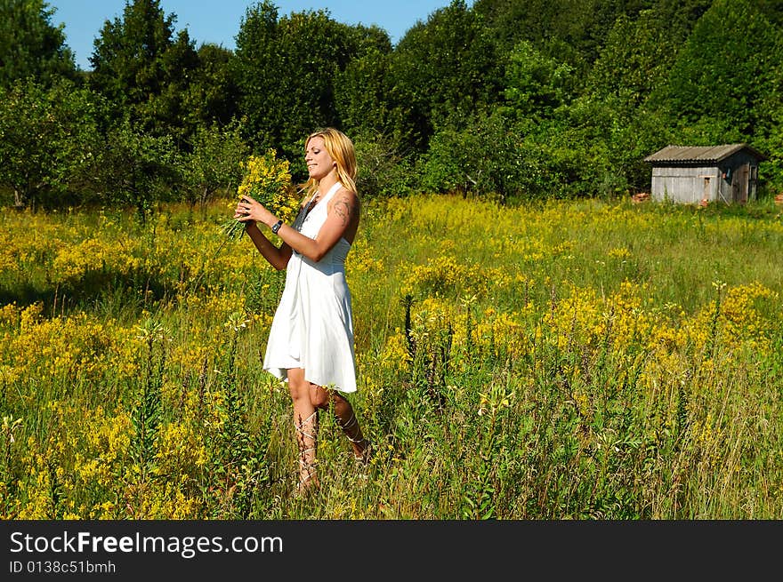 Blond woman in white dress on a meadow