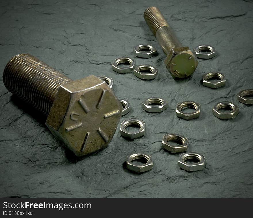 Brass nuts and bolts on textured surface. Brass nuts and bolts on textured surface