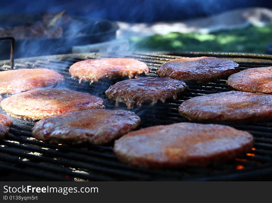 Set of Hamburger patties sitting on a flamed charcoal grill. Set of Hamburger patties sitting on a flamed charcoal grill.