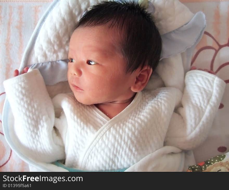 Lovely baby in white on a bed